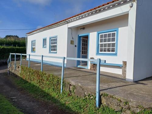 a small white house with a blue door at A Barraka: rent your room in Flores! in Lajes das Flores