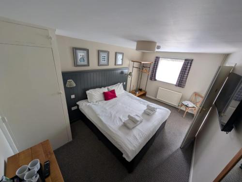 a bedroom with a bed with white sheets and red pillows at The Bull Hotel in Downton