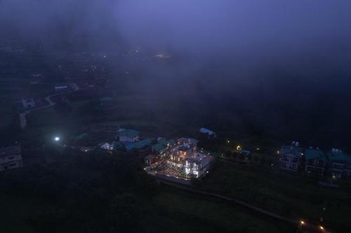 a foggy city at night with a house on a hill at Jags-N-Kals in Bhīm Tāl