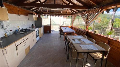 eine Küche mit Tischen und Stühlen in einem Zimmer mit Fenstern in der Unterkunft Casa NICORAD Camere in Pucioasa