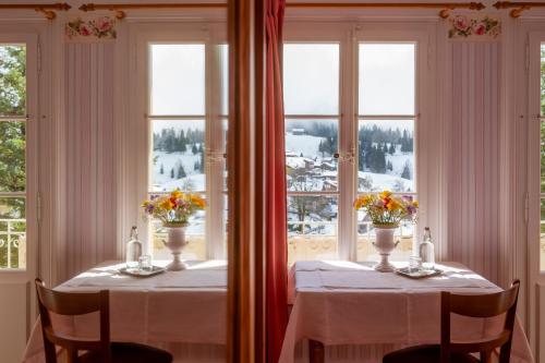 two tables in a room with windows with flowers on them at Historic Hotel Falken in Wengen