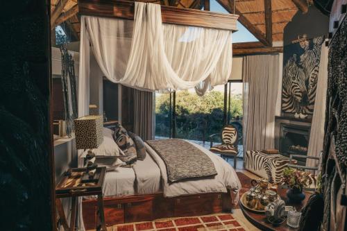 a bedroom with a bed in a room with a window at Thakadu Bush Lodge Naka Sanga in Mabula