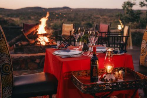 a table with wine glasses and a fire place at Thakadu Bush Lodge Naka Sanga in Mabula
