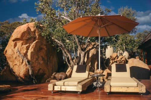 two chairs and an umbrella on a patio at Thakadu Bush Lodge Naka Sanga in Mabula