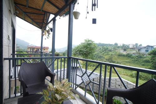 a balcony with two chairs and a view at Jags-N-Kals in Bhīm Tāl