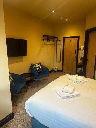 a room with a bed and two chairs and a tv at The Goodrington Sands- Apart Hotel in Paignton