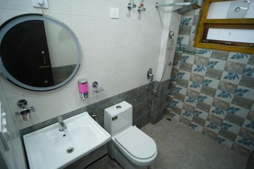 a bathroom with a sink and a toilet and a mirror at Jags-N-Kals in Bhīm Tāl