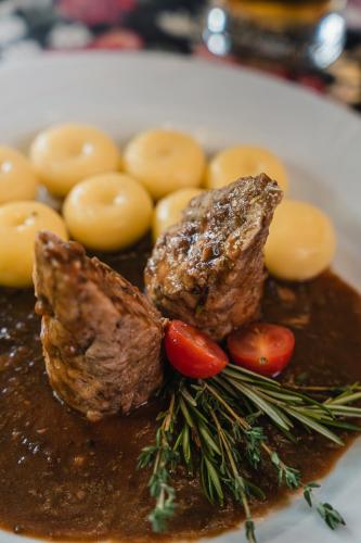 a plate of meat and gravy with potatoes and tomatoes at Zamek Czocha in Leśna