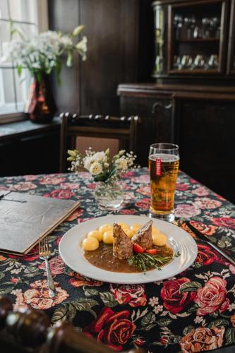 a plate of food on a table with a glass of beer at Zamek Czocha in Leśna
