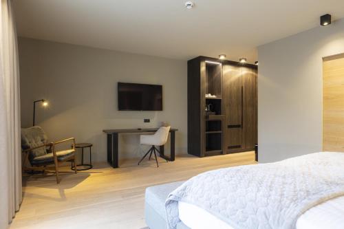 a bedroom with a bed and a desk and a tv at Berg & Golf Resort Westendorf by ALPS RESORTS in Westendorf