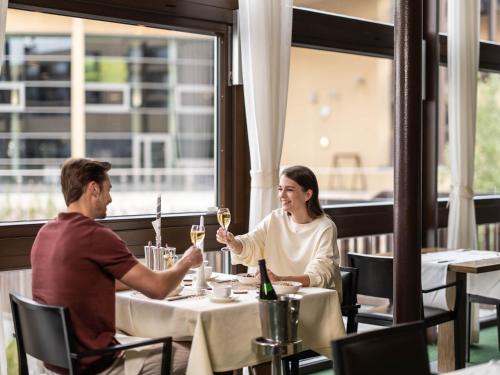 a man and woman sitting at a table with glasses of wine at St. Martins Therme & Lodge in Frauenkirchen