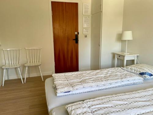 a bedroom with a bed with two chairs and a door at Korinth Kro Hostel - Betjeningsfrit vandrehjem in Fåborg