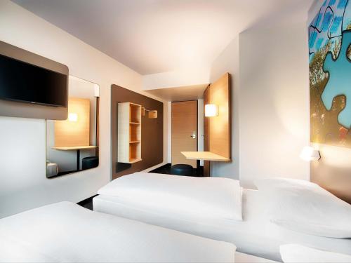 a hotel room with two beds and a flat screen tv at B&B Hotel Ravensburg in Ravensburg