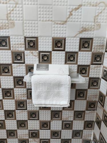 a tiled bathroom with a white towel and pictures on the wall at Harigarh Inn in Alīgarh