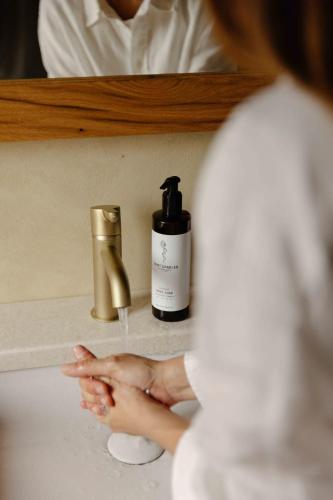 a woman is washing her hands in front of a bathroom sink at La Ghiandaia Farmhouse in Scomigo