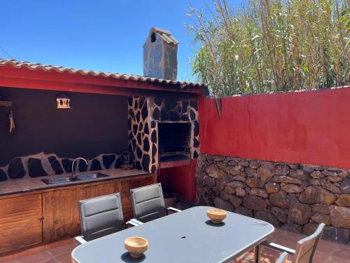 a patio with a table and chairs and a stone wall at Casa La Gollada in Cazadores