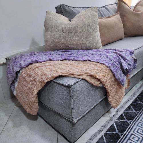 a couch with a purple blanket on top of it at joli studio avec terasse au coeur harhoura in Temara