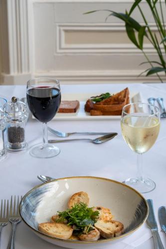 a table with a plate of food and two glasses of wine at Grand Hotel Swanage in Swanage