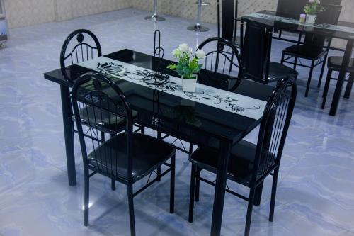 a black table with black chairs and flowers on it at Peace Star Hotel in Wa