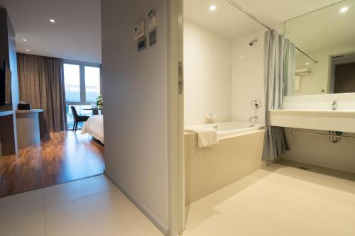 a bathroom with a sink and a bath tub at New Season Square Hotel in Hat Yai