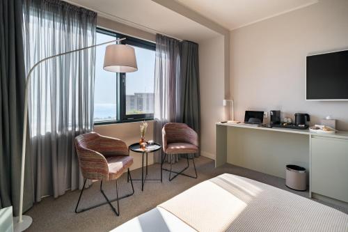 a hotel room with a bed and a desk and chairs at Millennium Hub & Hotel in Constanţa