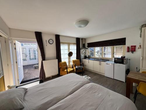 a bedroom with a large bed and a kitchen at Appartement Villa Eva Rosa in Wijk aan Zee