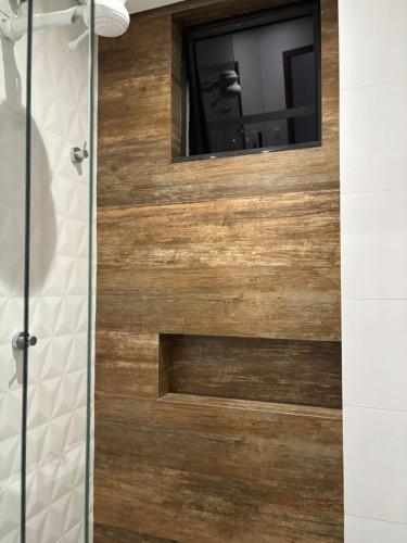 a bathroom with a wooden door with a mirror at Apartamento novinho e central - 2 ou 3 quartos, 2 banheiros, elevador e estacionamento in João Monlevade