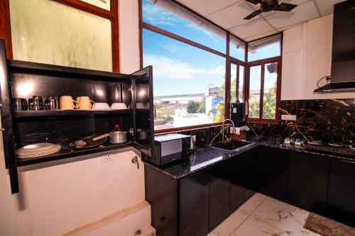 a kitchen with black counters and a sink and a window at Oasis Homestay Kochi in Ernakulam