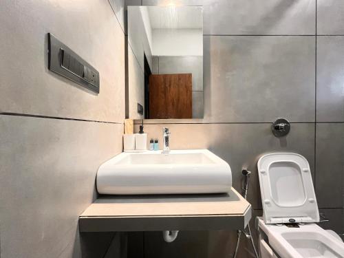 a bathroom with a sink and a toilet and a mirror at Unwind Karjat in Palasdhari