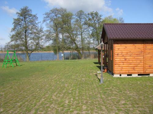 a small wooden cabin with a playground in the grass at Domki Letniskowe ARKON in Strykowo