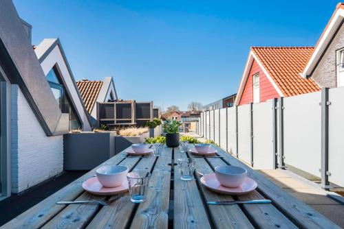 a wooden table with plates and glasses on a balcony at Weststraat 22 - Ouddorp - Appartement Oost 3P in Ouddorp