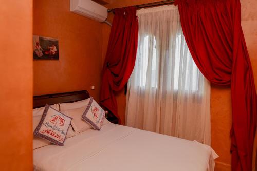 a bedroom with a bed with red curtains and a window at Maison d'Hôtes Akchour in Chefchaouene
