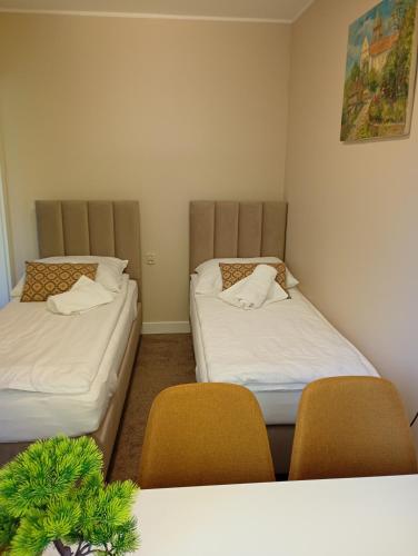 two beds in a room with two chairs and a table at Deluxe Apartament z tarasem i parkingiem na wyłączność in Ciechanów