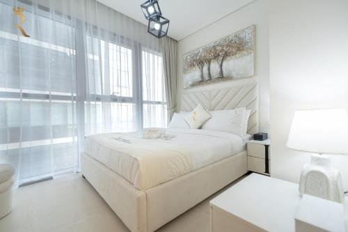 a white bedroom with a large bed and a window at Stylish 2BR - Chic Elegant Urban Escape in Abu Dhabi