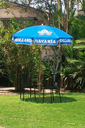 two chairs under a blue umbrella in the grass at StayVista at Anjali with Free Breakfast & Terrace Access in Kozhikode