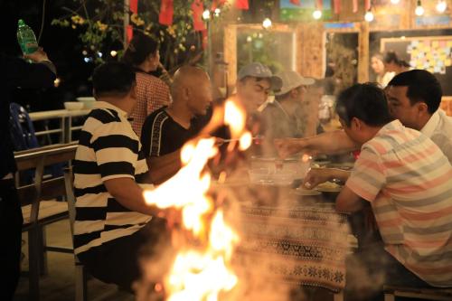 a group of people sitting around a table with a fire at Sapa Succulent Garden Homestay in Sa Pa