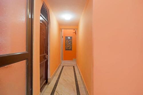 un pasillo con una pared de color naranja y una puerta en FabHotel Baba Guest House, en Varanasi