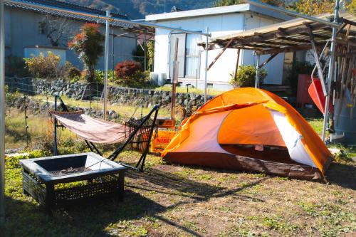 an orange tent and a hammock in a yard at 淵明庵 in Fujikawa