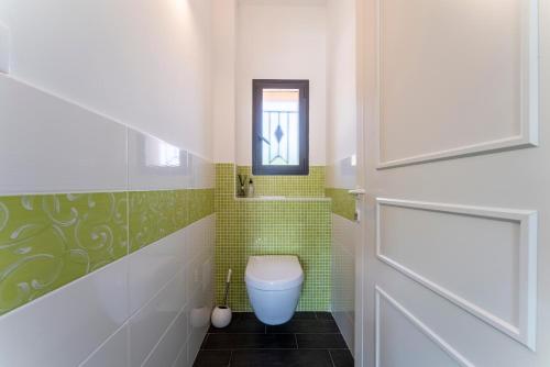 a bathroom with a toilet and a green tiled wall at Villa L'ecrin Du Ventoux in Crillon-le-Brave