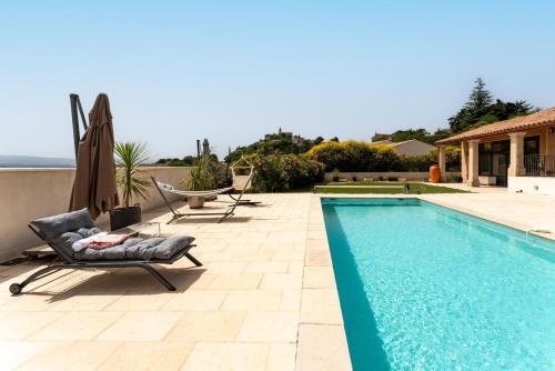 a swimming pool with a chair and a recliner next to a house at Villa L'ecrin Du Ventoux in Crillon-le-Brave