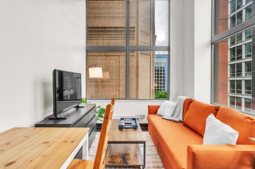 sala de estar con sofá naranja y TV en CozySuites Modern 1BR in Downtown Pitts #20, en Pittsburgh