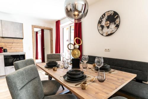 a dining room table with chairs and a clock on the wall at Apart Hotel Alpenhof Werfenweng in Werfenweng