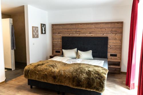 a bedroom with a large bed with a wooden headboard at Apart Hotel Alpenhof Werfenweng in Werfenweng