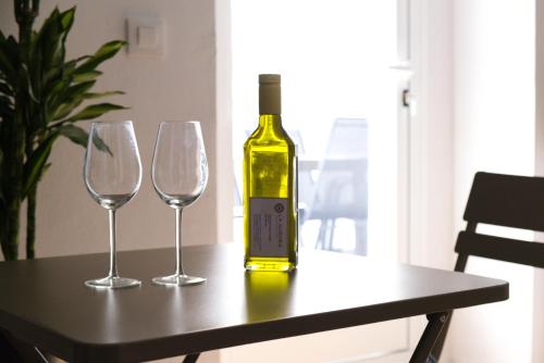 a bottle of wine sitting on a table with two wine glasses at La Casa del Gallo Alojamientos by Taberna Bolero in Montilla