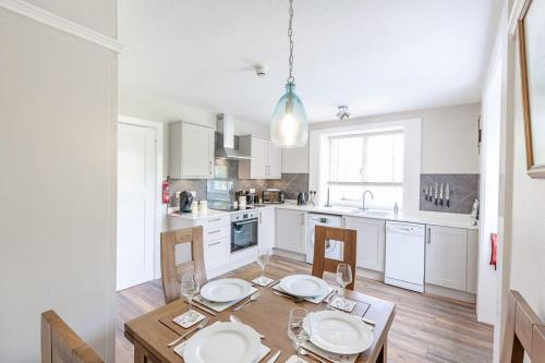a kitchen with a wooden table with chairs and a dining room at Lonan Country House and Gardens in Taynuilt