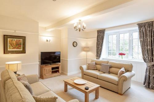 a living room with two couches and a tv at Lonan Country House and Gardens in Taynuilt