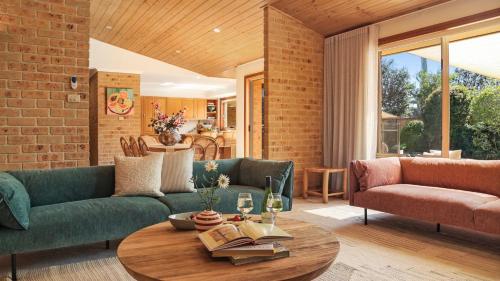 a living room with two green couches and a table at Coolburra in Culburra Beach
