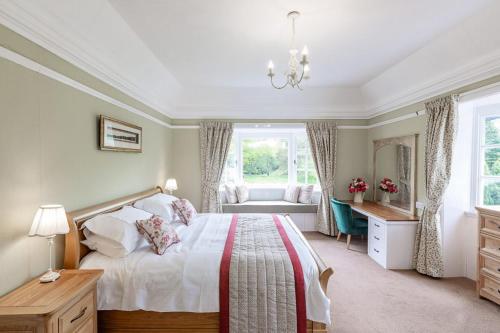 a bedroom with a bed and a desk and a window at Lonan Country House and Gardens in Taynuilt