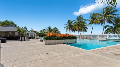 ein Swimmingpool mit Palmen und dem Meer in der Unterkunft Beachfront 7th floor unit at Mar Azul in Aguada