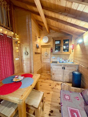 a wooden cabin with a table and a kitchen at La Cabane à l'Orée des Bornes in Évires